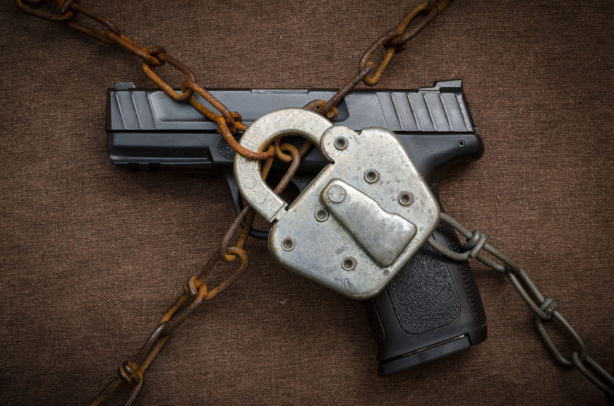 A gun behind chains with a padlock.